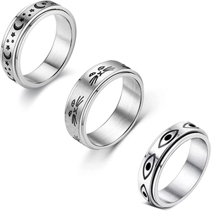 Macro detail of three silver rotating spinner rings with moon, star, and eye engravings