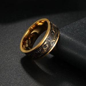 Detail of vintage gold-plated steel ring with black embossed floral scroll patterns