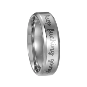Détail macro d'une bague en acier argenté avec le texte gravé keep fucking going