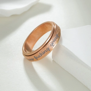 Macro shot of rose gold spinner ring with matte texture and keep fucking going engraving