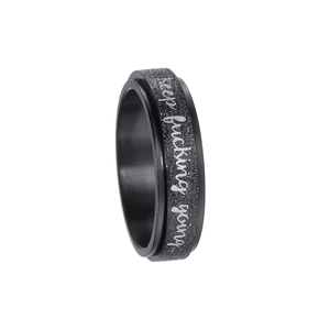Detail of black stainless steel spinning ring with sandblasted finish and engraved text