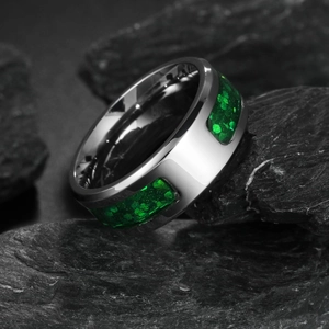 Modern silver steel ring with green faux opal inlay on dark textured stone background