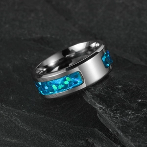 Polished men's ring with blue synthetic opal inlay on dark grey rock background