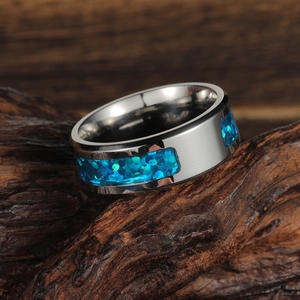 Macro shot of silver stainless steel band ring with blue opal inlay on wood surface