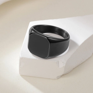 Minimalist square signet ring for men in brushed black stainless steel on stone stand