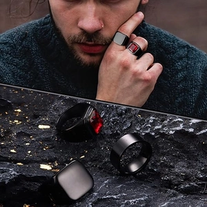 Detail of three-piece men's black titanium rings featuring a red ruby inlay on stone background