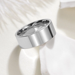 Detailed close-up of wide silver stainless steel ring with mirror finish on white surface