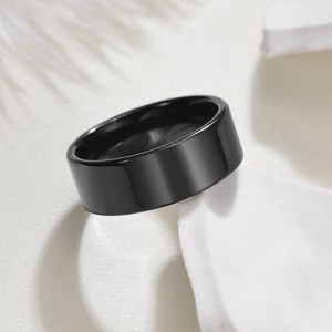Close-up of polished black stainless steel band ring with flat edge on minimalist background