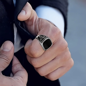 Gros plan d'une bague pour homme en acier argenté avec onyx noir et nœuds celtiques