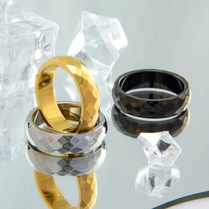 Macro view of three geometric faceted titanium steel rings in gold, silver, and black colors