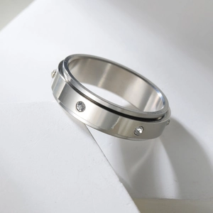 Bague rotative en argent poli avec strass blancs sur support géométrique blanc