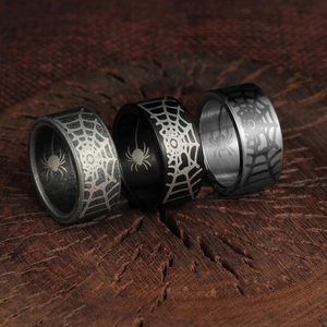 Macro view of three gothic spider web rings in silver and black on wood background