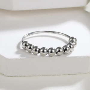 Antistress-Ring aus poliertem Edelstahl mit zehn beweglichen Perlen auf weißem Stein