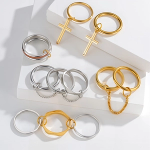 Dettaglio macro di anelli sovrapposti in oro e argento con ciondoli a croce e catenelle