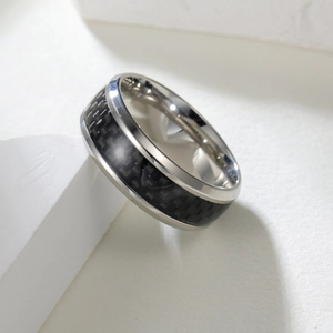 Macro detail of 8mm black titanium ring with blue carbon fiber inlay and polished edges