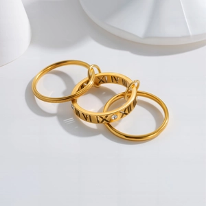 Interlocked gold titanium steel rings with Roman numerals and cubic zirconia accents