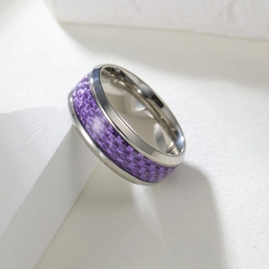 Macro shot of silver titanium ring featuring purple carbon fiber inlay on white stone