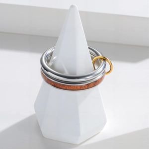 Minimalist stainless steel ring set featuring wood inlay and silver finish on white stand