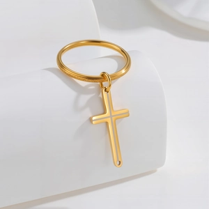 Bague en acier inoxydable doré avec pendentif croix sur fond blanc minimaliste