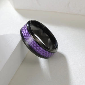 Macro view of a black titanium steel ring featuring a purple carbon fiber inlay design