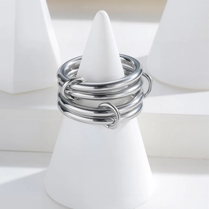 Modern four-layer interlocking silver metal rings on a white display stand