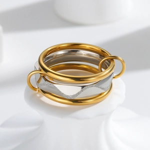 Set di tre anelli sovrapponibili con bande dorate e anello argento su base bianca minima