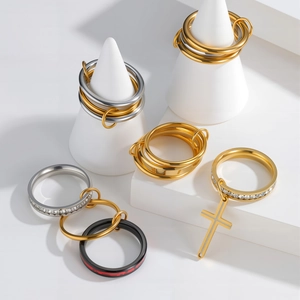 Macro detail of multi-layered gold and silver stacked rings with opal and cross charm