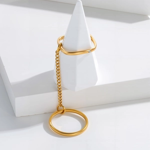 Detail of gold chain tassel ring with square band and sparkling diamond on white props