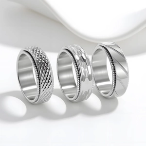 Three men's 8mm titanium steel spinner rings with knurled edges and textured patterns