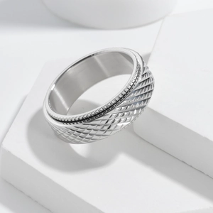 Macro detail of silver stainless steel ring featuring textured diamond pattern surface