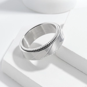 Macro detail of silver stainless steel rotating ring with knurled edges and textured lines