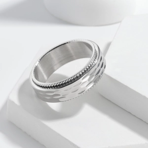 Macro detail of 8mm silver spinner ring featuring hammer texture and industrial gear edges