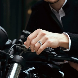 Men's punk style stainless steel spinner ring with spiral texture on a motorcycle grip