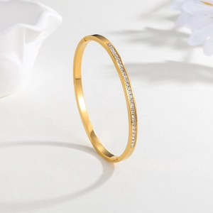 Bracelet jonc élégant en acier titane doré avec une rangée de zircons sur fond blanc