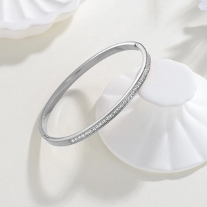 Bracelet jonc en acier titane poli avec zircons carrés sur support en céramique blanc