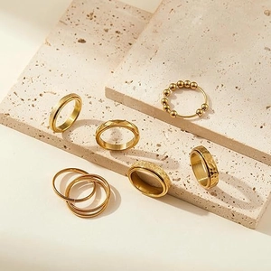 6-piece gold spinner ring set with star moon patterns on a travertine stone display
