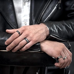 Close-up of a men's titanium steel ring set featuring black meander patterns and silver bands