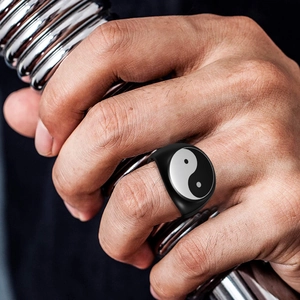 Detail of matte black Tai Chi ring on finger holding metal gym equipment
