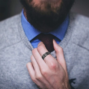 Close-up of a vintage stainless steel cross ring worn by a man in a business outfit