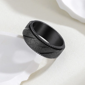 Détail d'une bague en acier noir mat de 8mm avec bords crantés et rainures usinées