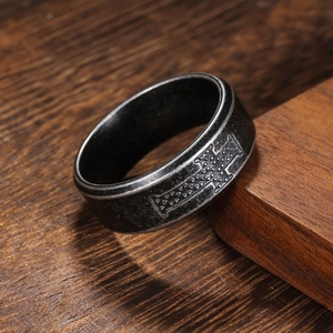 Vintage oxidized stainless steel cross ring with textured dots on dark wood surface