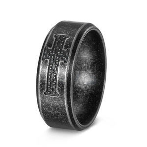 Macro shot of vintage stainless steel cross ring with textured matte finish and engraving