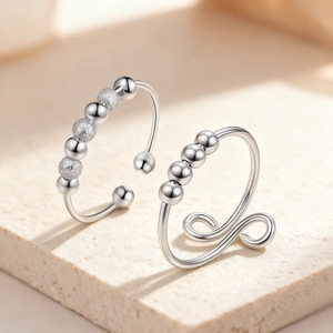 Silver rotating anxiety rings with polished beads on minimalist stone display