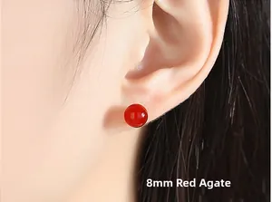 Close-up of 8mm natural red agate stud earring worn by a model with soft lighting