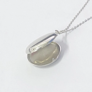 Macro detail of a polished S925 sterling silver oval locket pendant with a thin chain