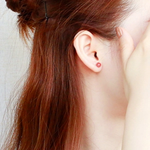Close-up of S925 silver strawberry crystal stud earring worn on model's earlobe