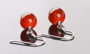 Vue macro des crochets d'oreilles en argent S925 avec perles d'agate rouge sur fond sombre