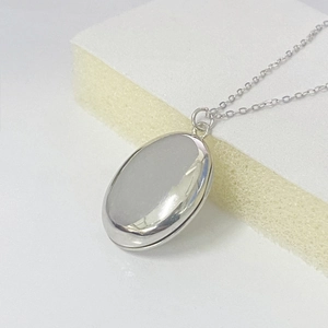 Polished S925 sterling silver oval locket necklace with fine link chain on display