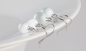 Macro detail of elegant S925 silver drop earrings with spherical white cat eye stones