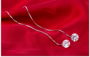 Close-up of long silver tassel earrings with zircon stones on red silk background